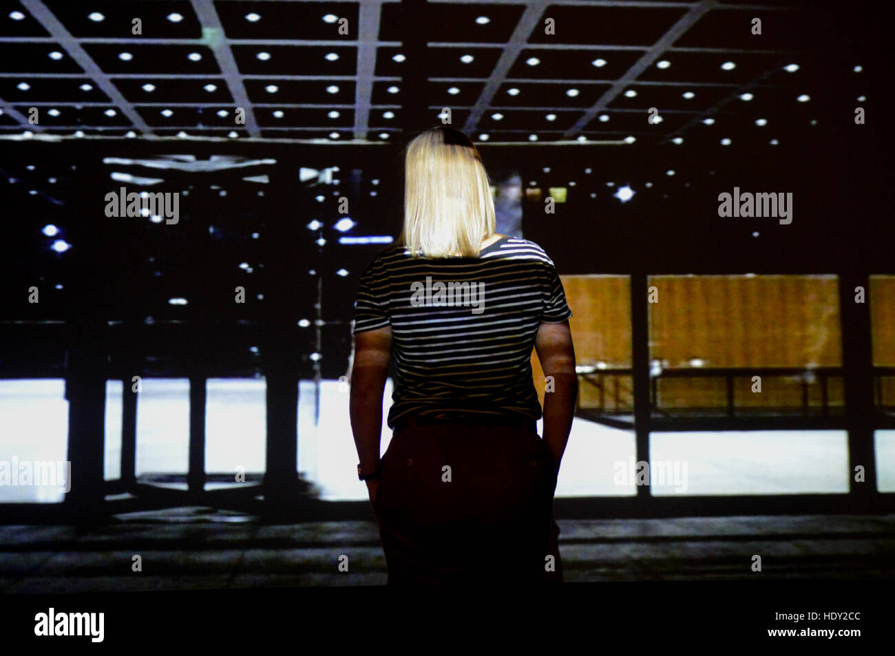 Una donna sta in piedi di fronte ad un proiettore la creazione di illuminazione creativa pattens all interno di un museo. Foto Stock