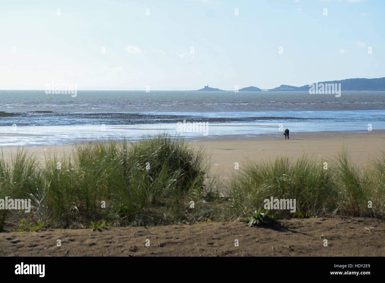 Un paio di camminare lungo la Baia di Swansea con testa borbotta qualcosa in background Foto Stock