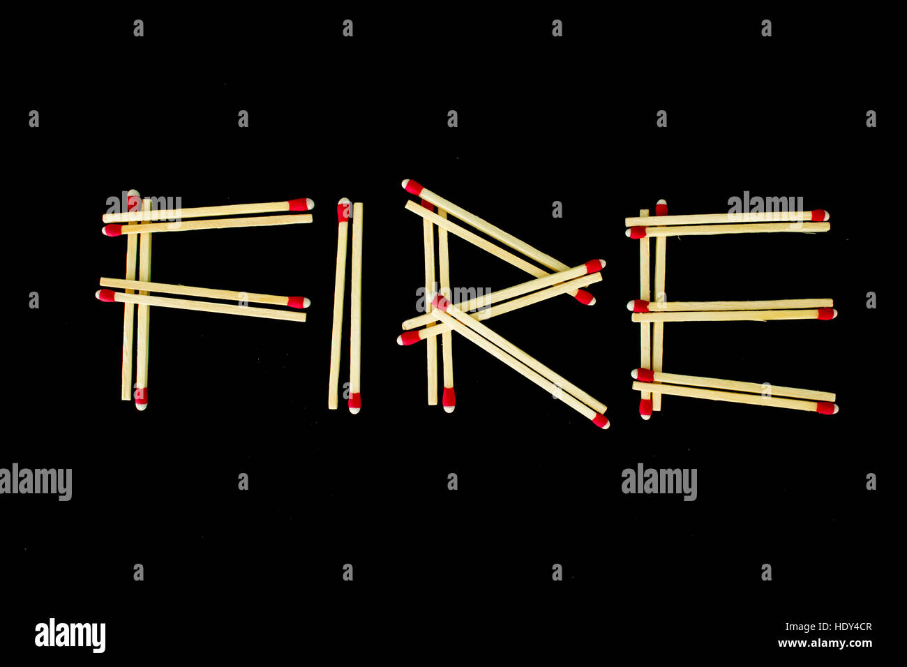 La parola 'fuoco' scritto con strike-anywhere corrispondenze, isolata su uno sfondo nero. Fotografato dal di sopra. Foto Stock