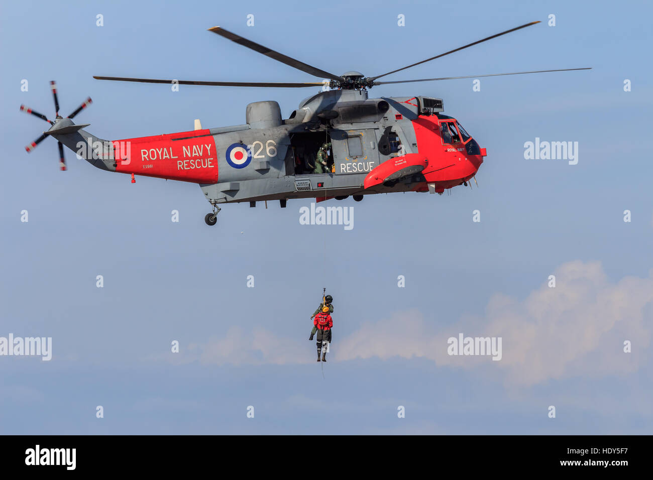 Royal Navy Seaking Ricerca e Salvataggio in elicottero di eseguire la simulazione di soccorso con equipaggio appeso dal verricello Foto Stock