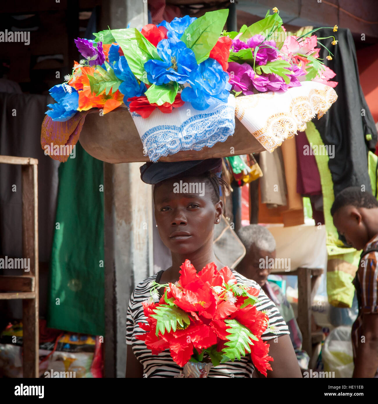 Adolescente africana portando un vassoio di oggetti decorativi Foto Stock