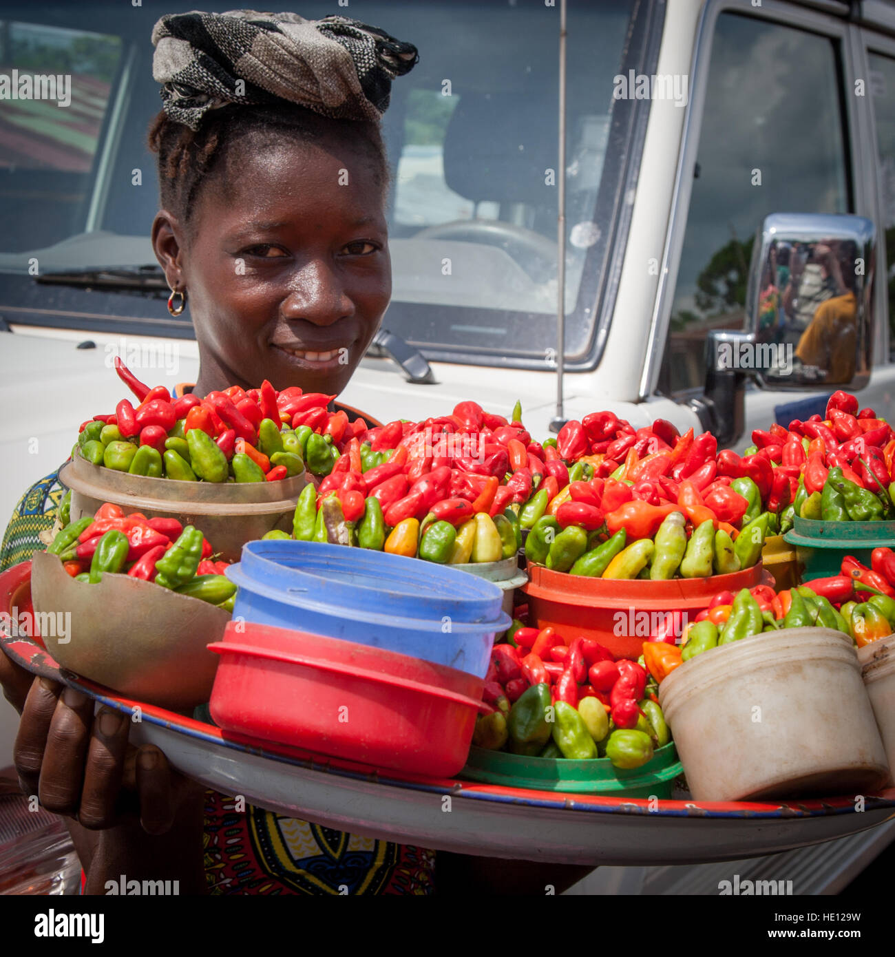 Venditore di strada di peperoncini piccanti freschi su un vassoio in Sierra Leone. Una qualsiasi di queste porzioni di peperoncino può riscaldare anche un pasto grande Foto Stock