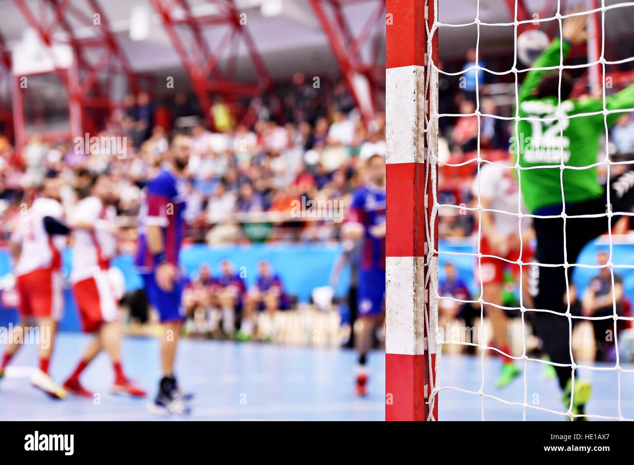 Azione di pallamano corrispondono a scena con goalpost e giocatori in background Foto Stock