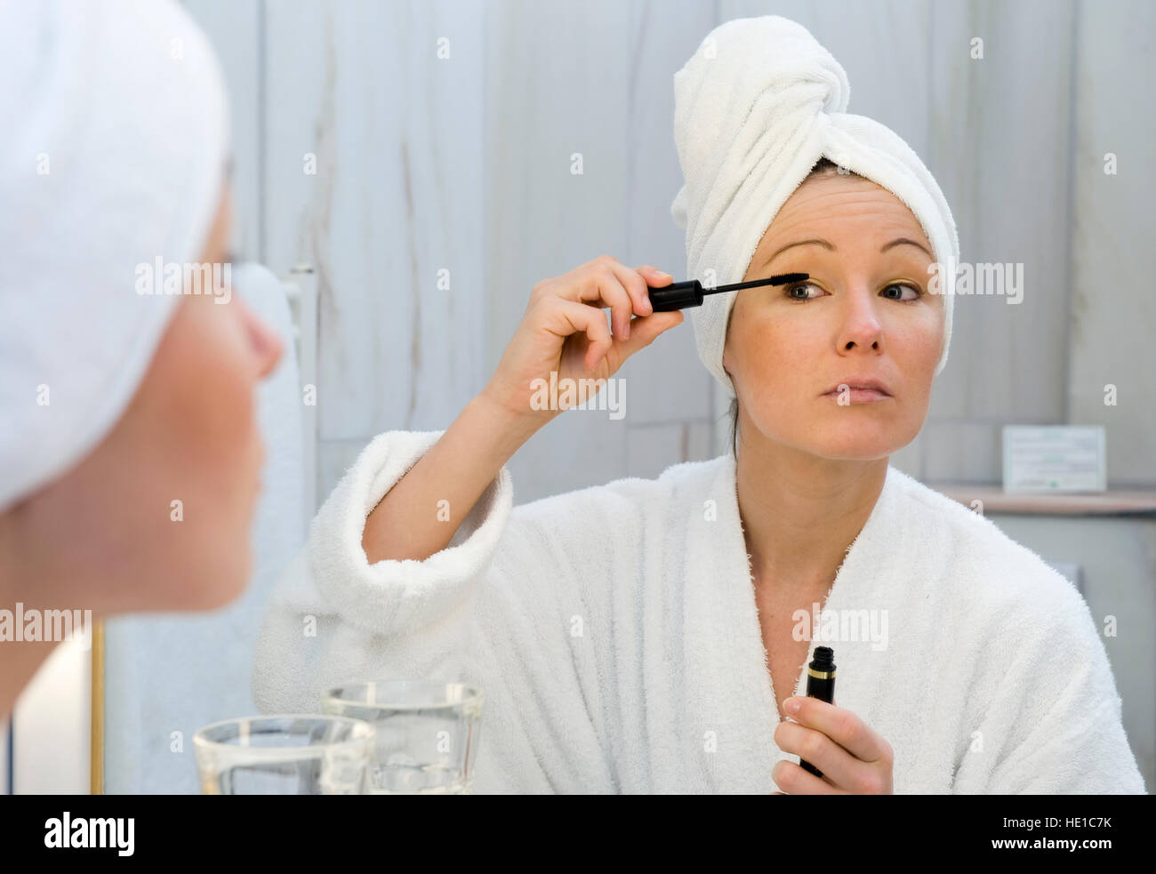 Giovane donna in bagno applicando, mettere il mascara Foto Stock