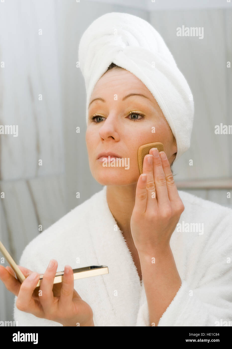 Giovane donna in bagno la polverizzazione di il suo volto Foto Stock
