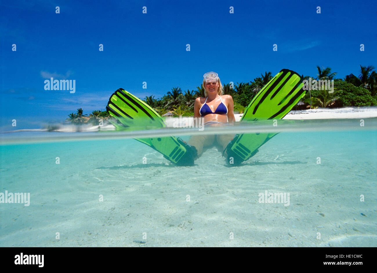 Metà e metà colpo di Maldive isola con una donna, 20, seduti in acqua con pinne, Summer Island Village, Nordmale Atoll Foto Stock