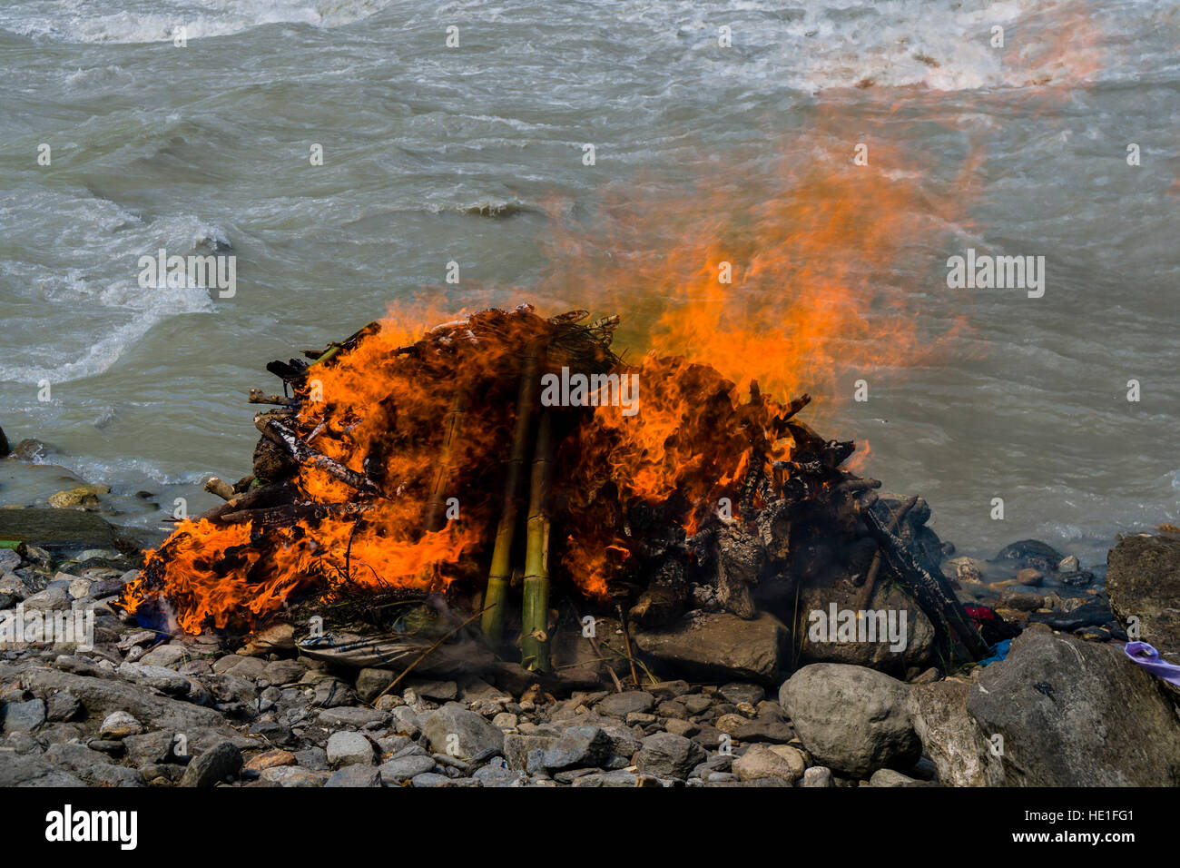 Il fuoco del funerale di un corpo di morte al suolo di cremazione sulla banca del fiume Kali Gandaki è bruciato Foto Stock