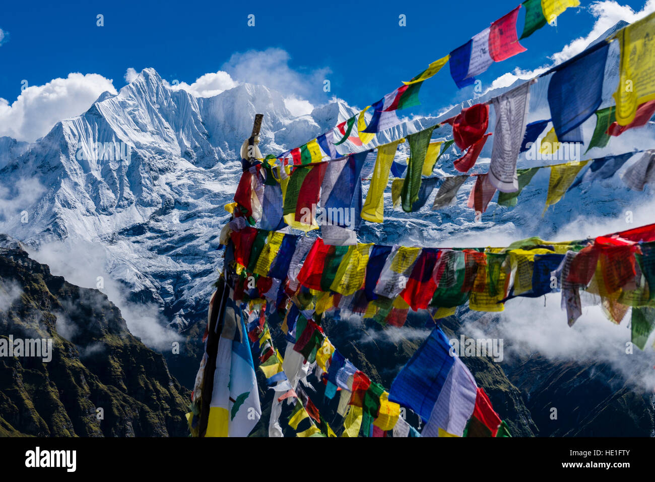 Molti tibetani bandiere di preghiera sono impostati ad una memotial per scalatori morì, la coperta di neve annapurna 1 North Face, parzialmente coperto dal monsone di nuvole, in th Foto Stock