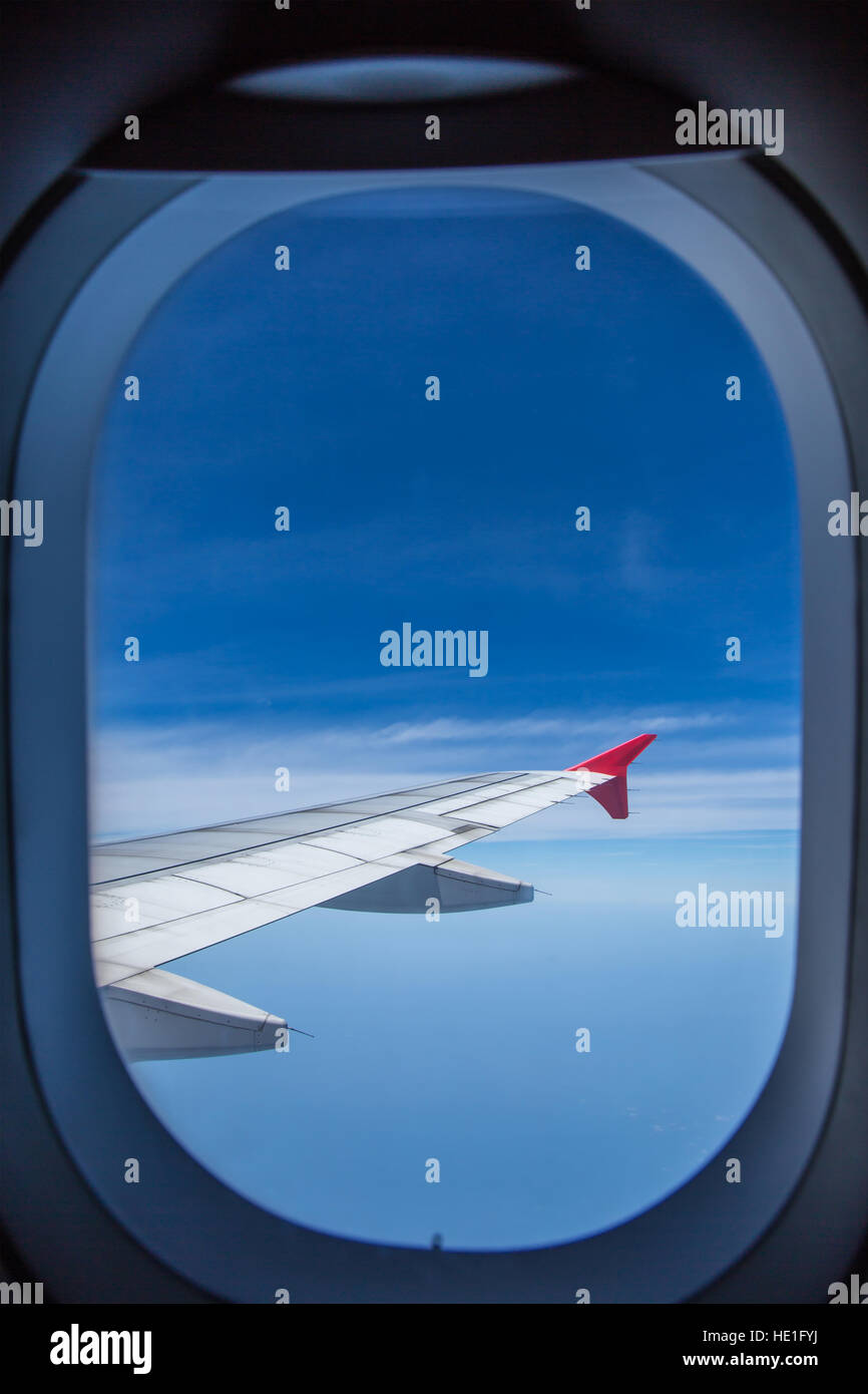 Vista dalla finestra di un'ala di aeroplano aerei volando sopra le nuvole in un cielo blu. Foto Stock