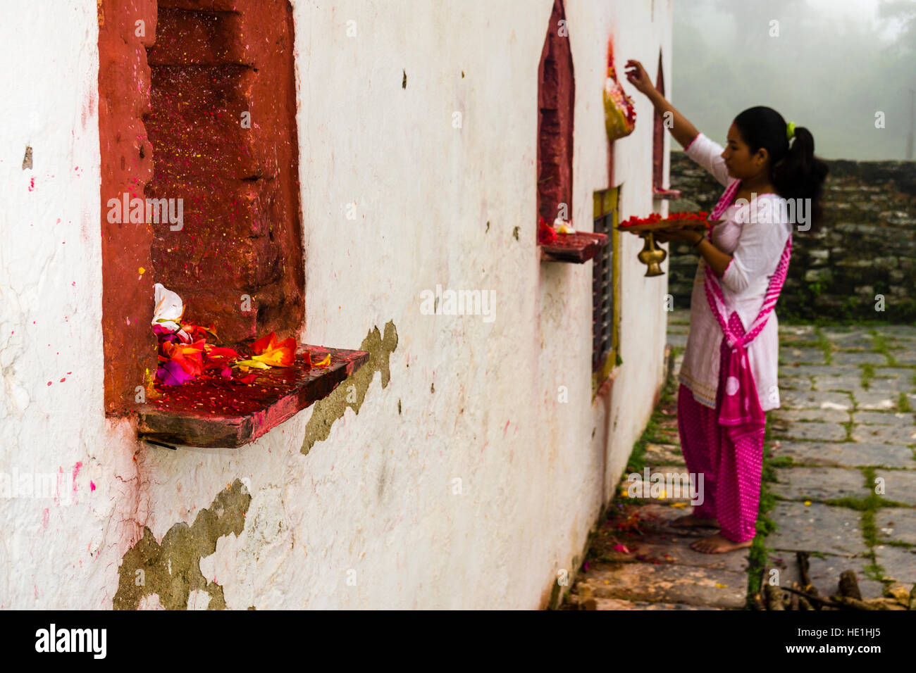 Una donna sta offrendo prasad per le statue di divinità al di fuori del tempio khadga devi mandir presso il festival indù, darsain Foto Stock