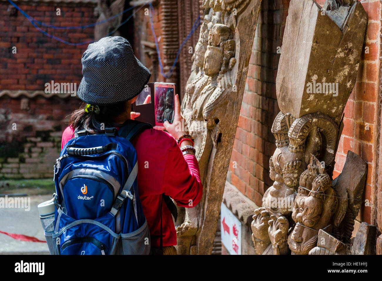 Una donna cinese è scattare una fotografia del abilmente intagliata in legno figure a hanuman dhoka palace Foto Stock