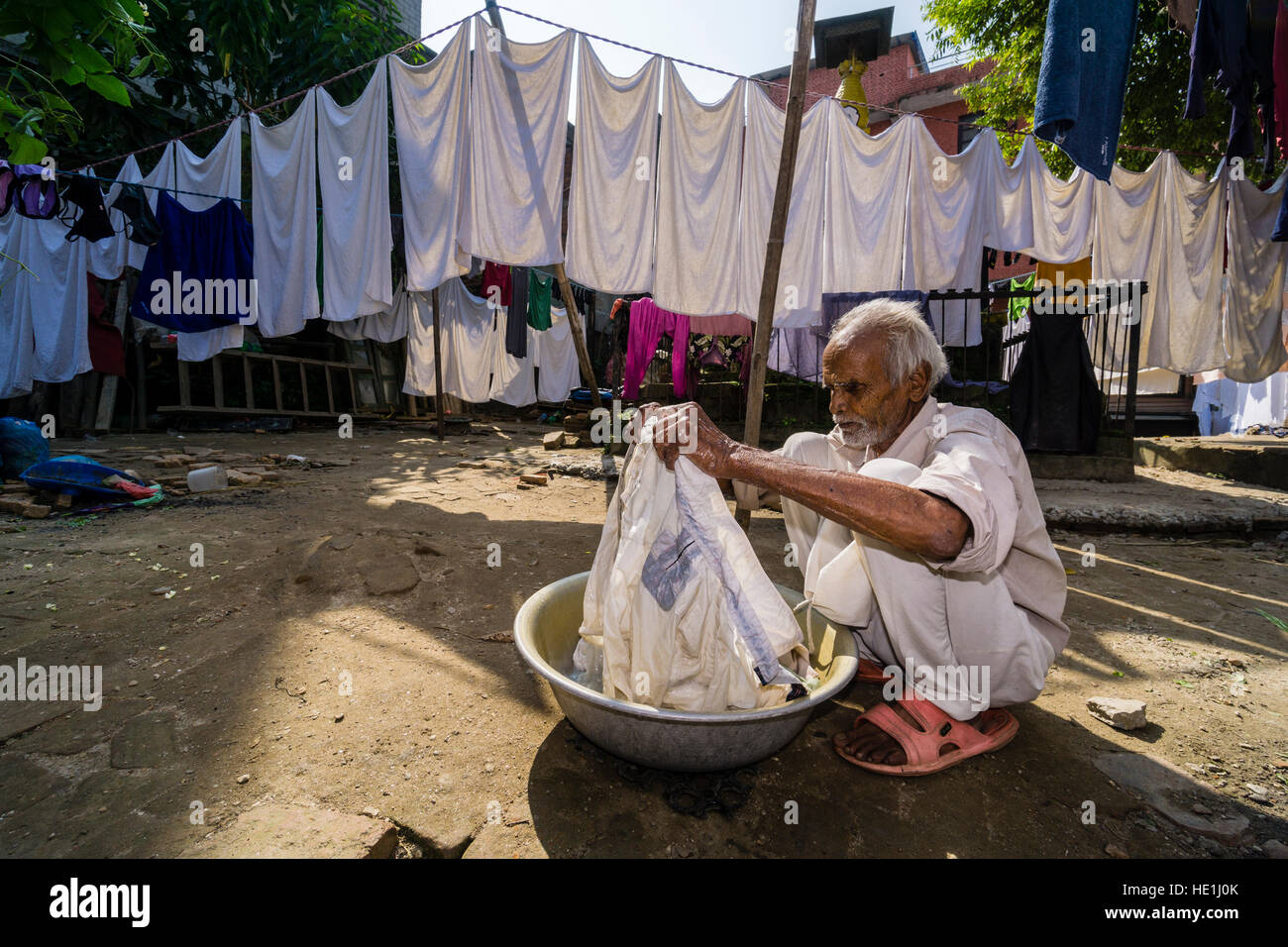 Un uomo sta facendo servizio lavanderia a mano in un cortile Foto Stock