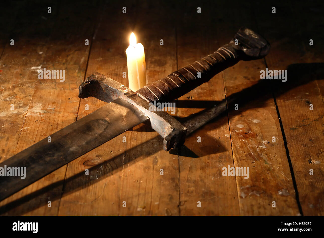 Wintage still-life con antica spada vicino alla candela di illuminazione sul pannello di legno Foto Stock