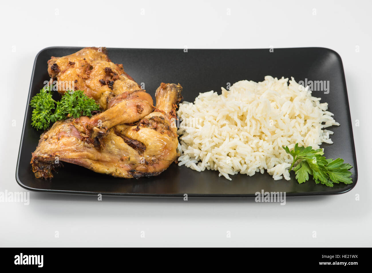 Grigliata di coscia di pollo con riso e prezzemolo sul tavolo della luce naturale Foto Stock