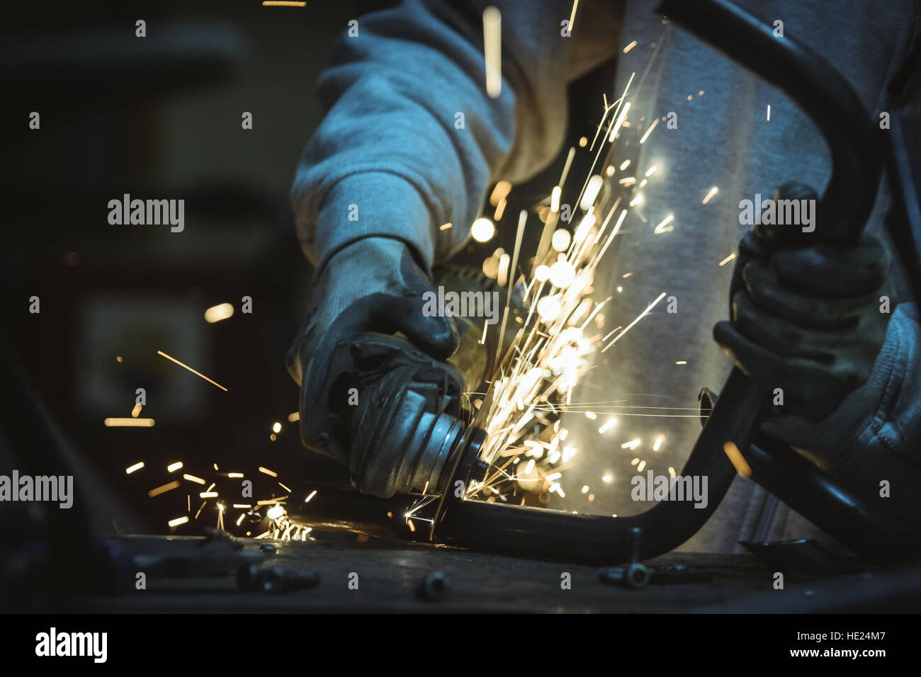 La formazione di scintille volanti in officina. Taglio della tubazione con una mola circolare. Foto Stock