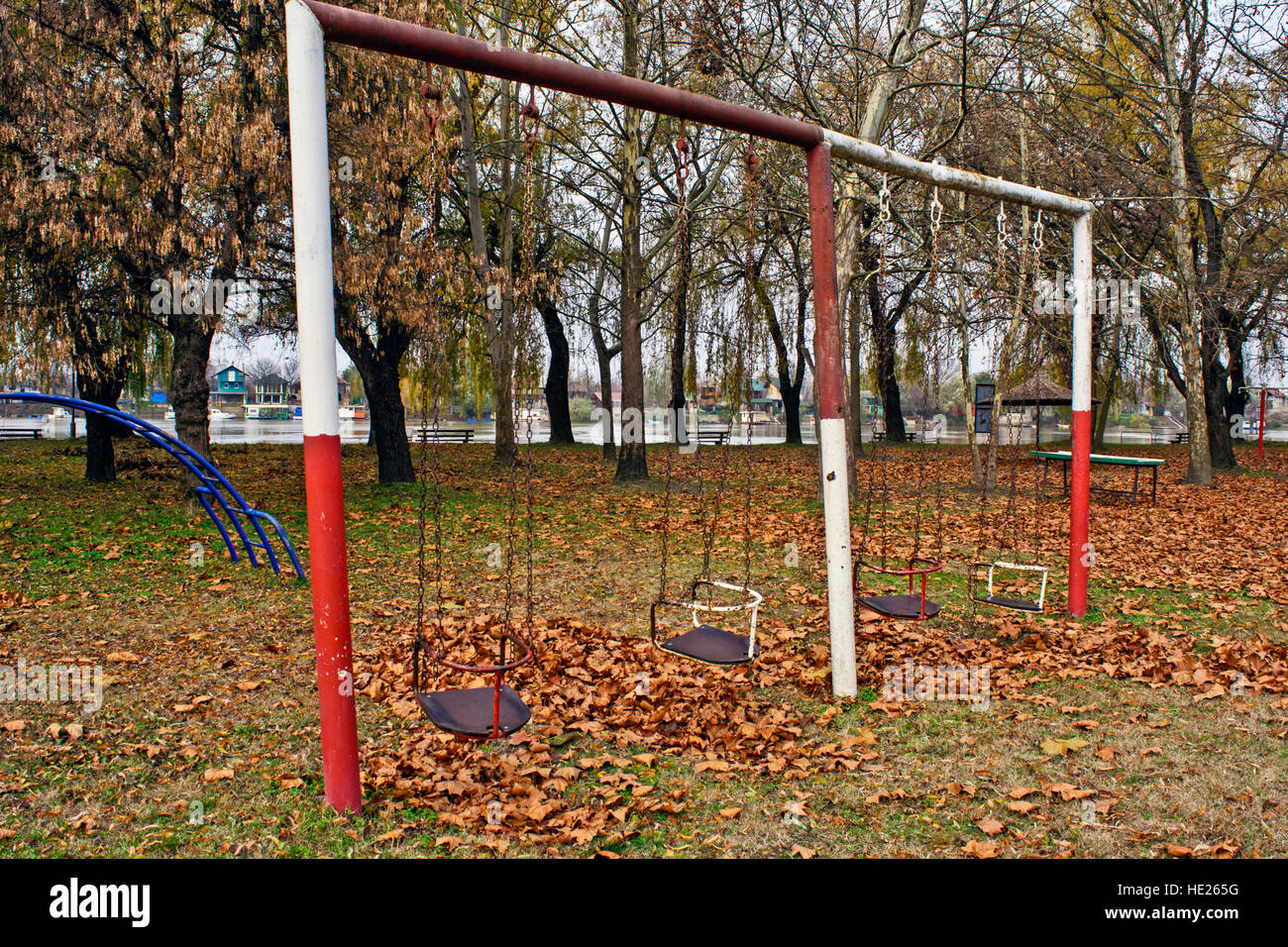 Un parco giochi vuoto sulla banca del fiume in autunno. Foto Stock