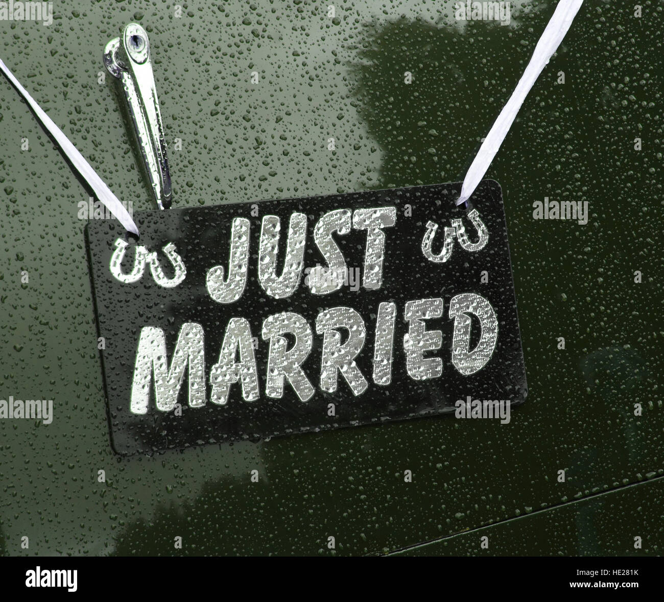 Appena sposato segno appeso sul retro di una vendemmia verde auto nozze sotto la pioggia. Foto Stock
