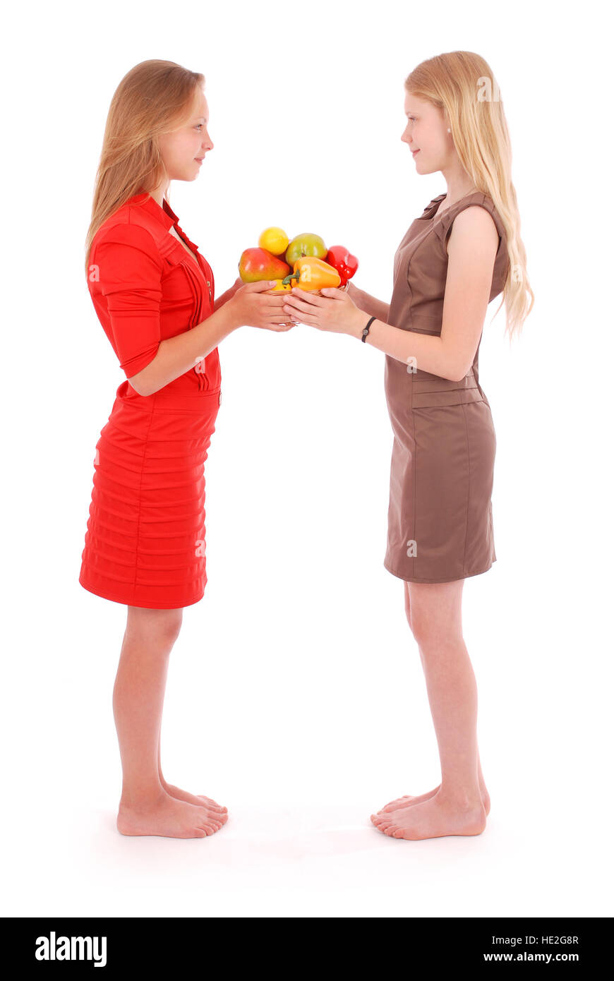 Due ragazza giovane con un cesto di frutta isolato su bianco Foto Stock