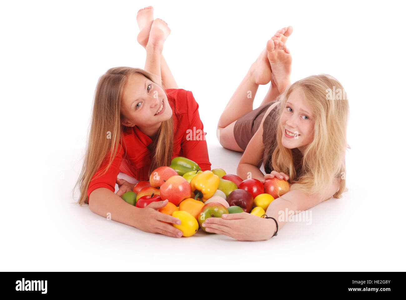 Due ragazze azienda frutta fresca isolato su bianco Foto Stock