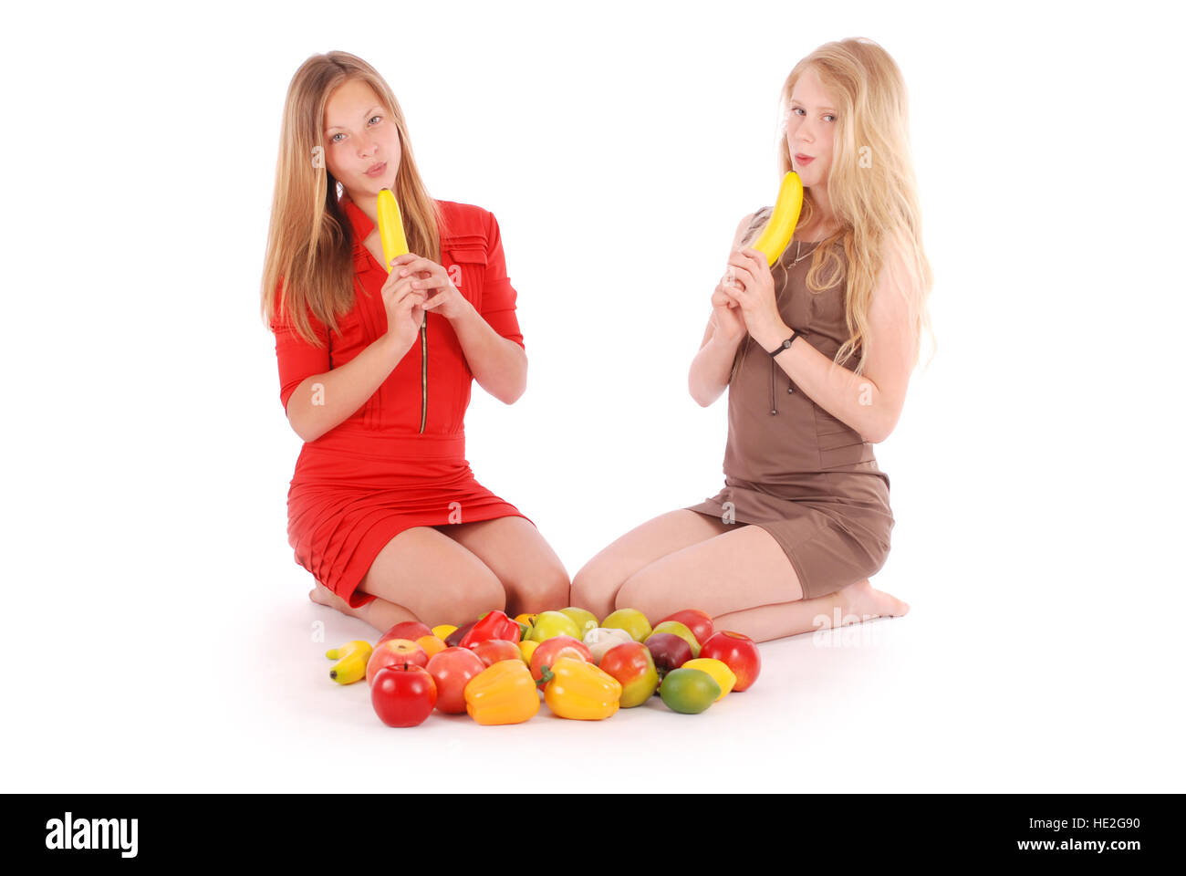 Due giovani girl tenere una banana come una delle pistole. Isolato su sfondo bianco Foto Stock