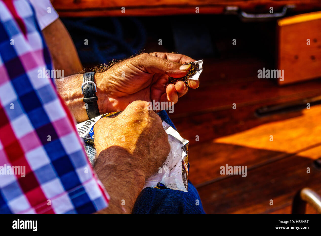 Sailor la laminazione di una sigaretta sulla durante un bot Ride su una tavola di legno Botter barca sul Veluwemeer nei Paesi Bassi Foto Stock