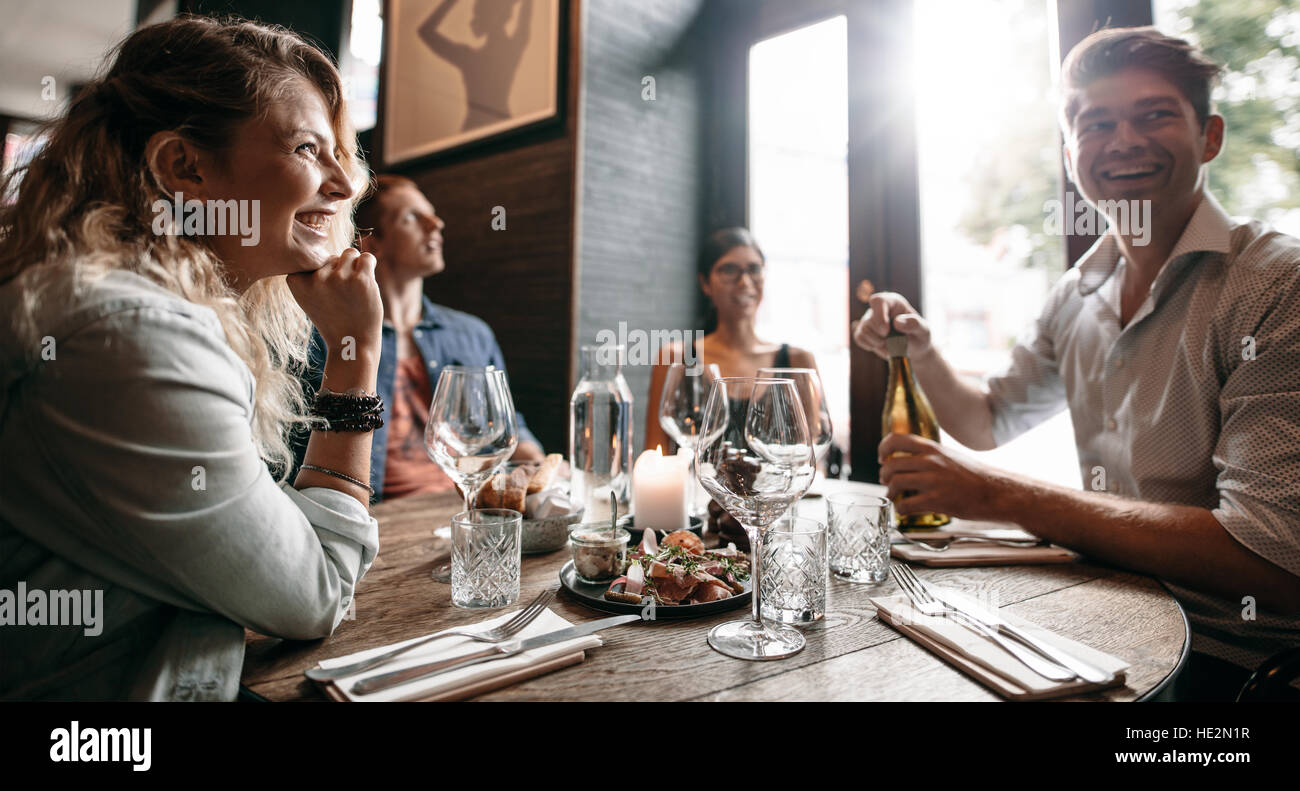 Gruppo di amici gustando un pasto serale con il vino al ristorante. Felice giovane uomo e donna con una cena in un ristorante. Foto Stock