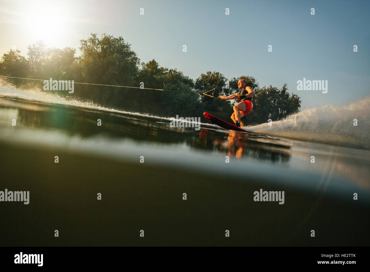 Atleta sci d'acqua dietro una barca. L'uomo wakeboarding sulle sponde di un lago. Foto Stock
