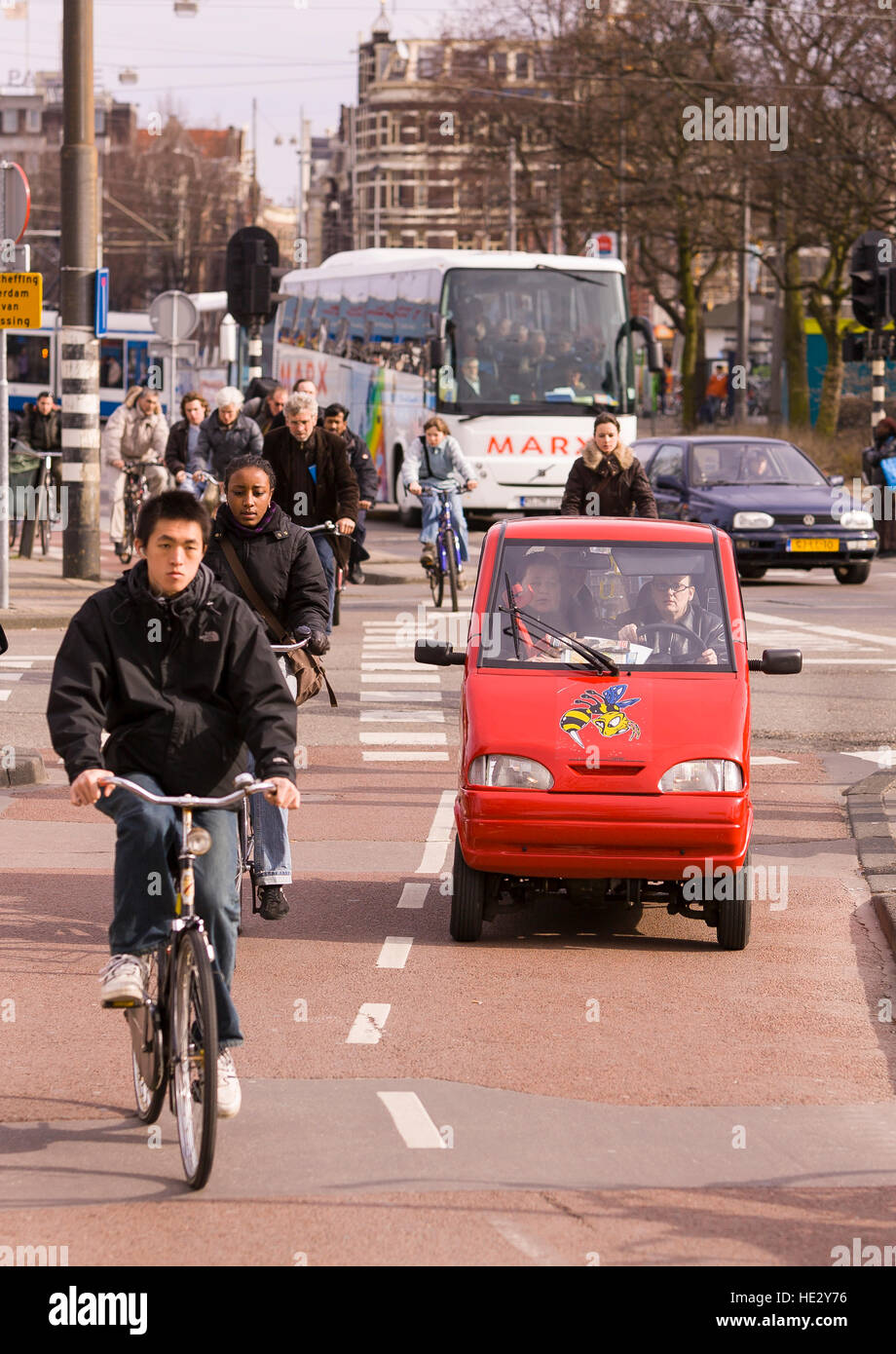 AMSTERDAM, PAESI BASSI - persone andare in bicicletta sulla pista ciclabile e la piccola vettura. Foto Stock