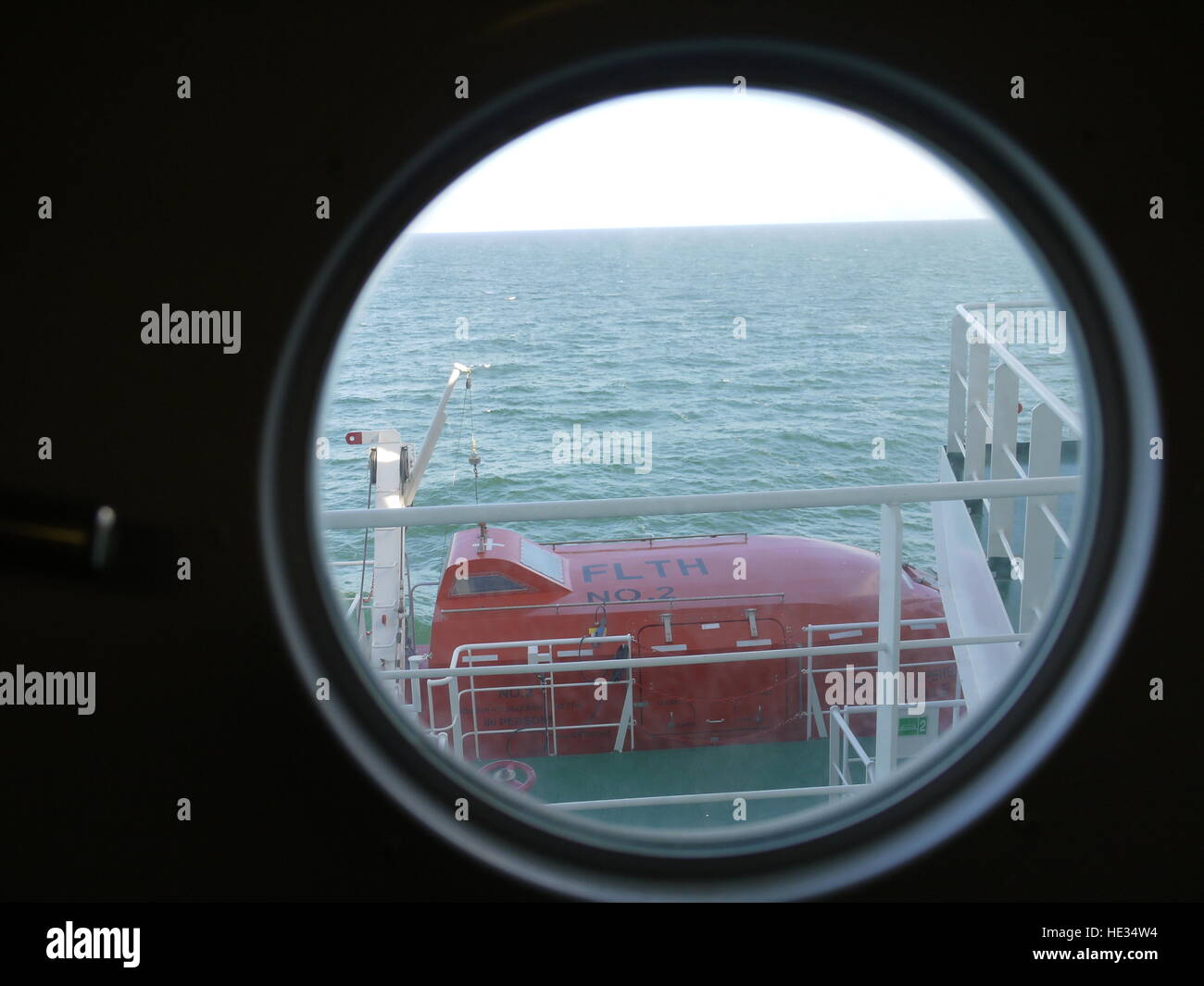 La sopravvivenza in canoa attraverso un oblò su una nave portacontainer in mare Foto Stock