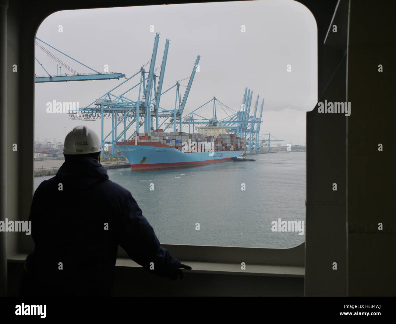 Nel merchandise porto di Amburgo, un marinaio guarda a una nave portacontainer dalla propria nave Foto Stock