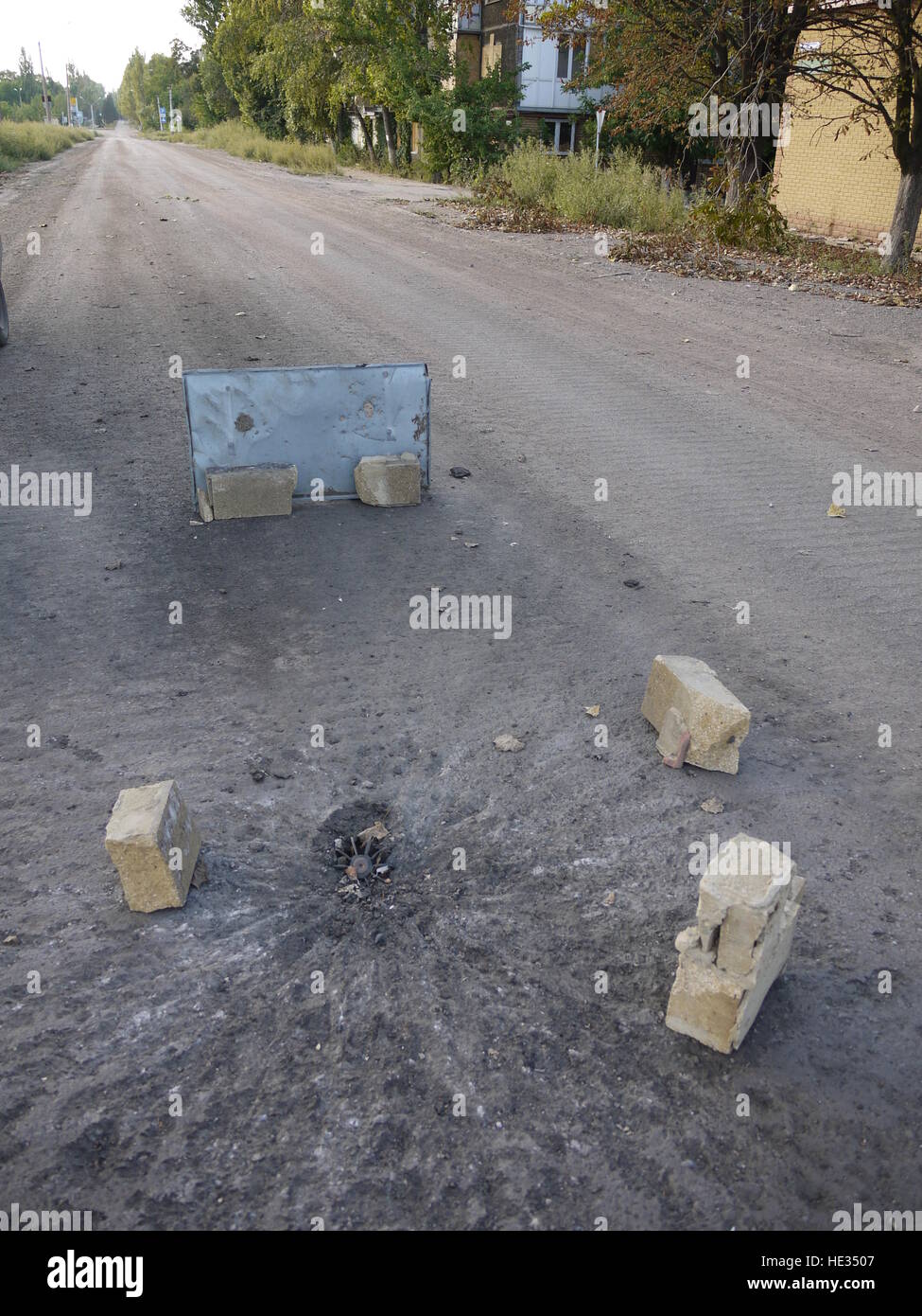 Un mortaio inesplose shell è caduto sulla strada dell'Ucraina orientale ed è semplicemente contrassegnati da un paio di pietre Foto Stock