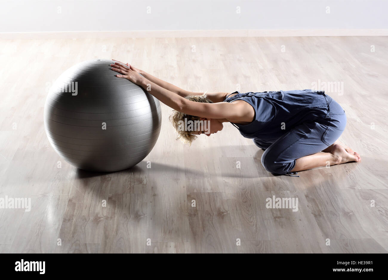 Montare la giovane donna facendo esercizi di pilates con una grande palla Foto Stock