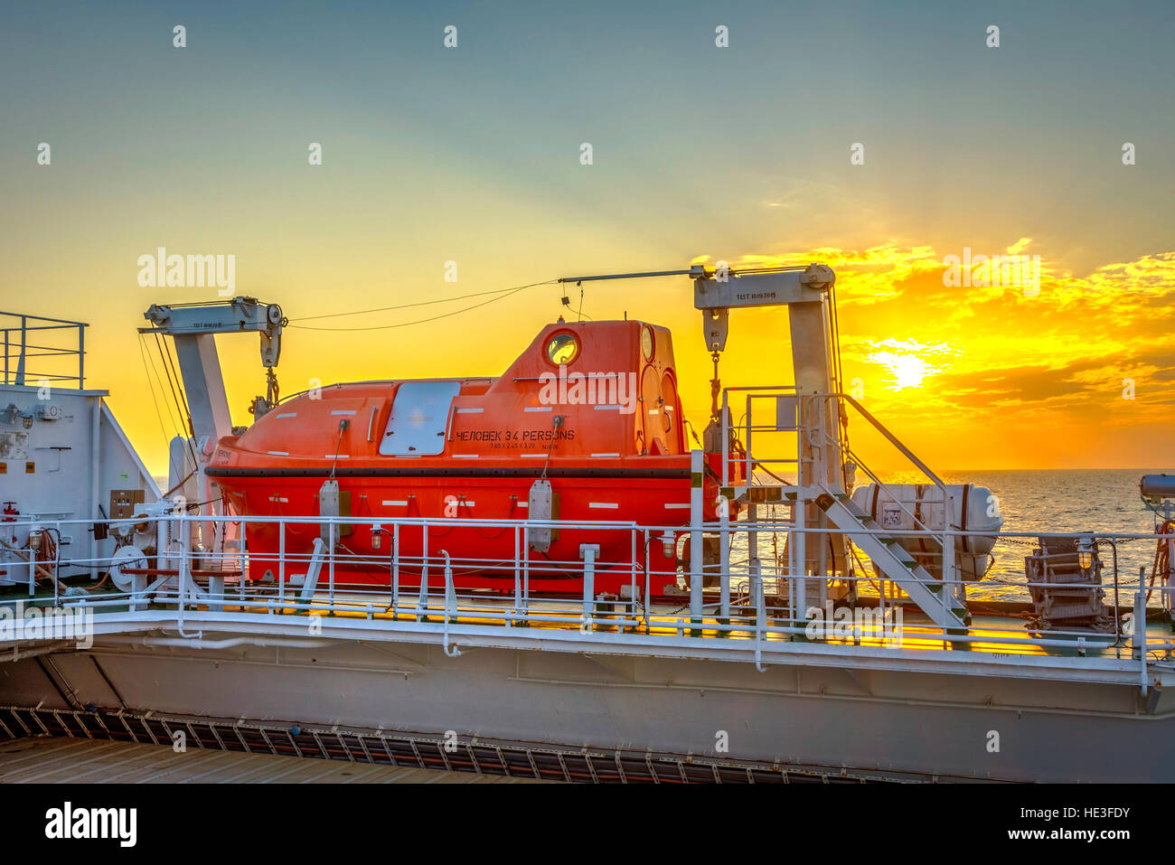 Orange la barca di salvataggio sulla nave in mare nel tramonto Foto Stock