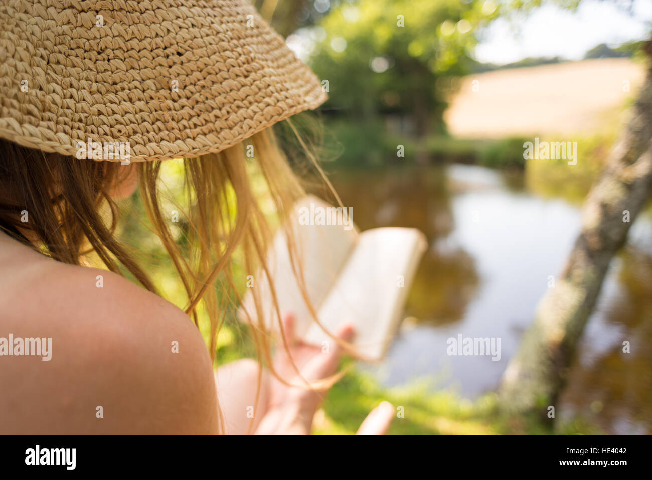 Donna con capelli dorati libro in natura in estate Foto Stock
