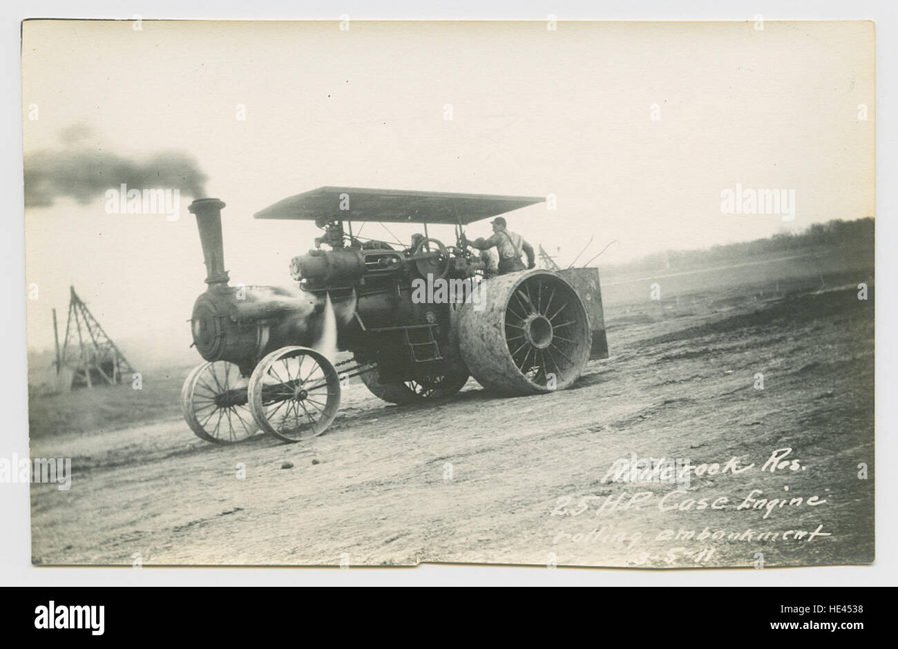 Questa immagine storica raffigura il Case Engine da 25 CV che rotola un terrapieno durante la costruzione di una diga presso il lago artificiale White Rock in Texas. Il motore, che fa parte dell'ingegneria dei primi anni del XX secolo, mette in evidenza il ruolo dei motori di trazione nello sviluppo delle infrastrutture idriche. Foto Stock