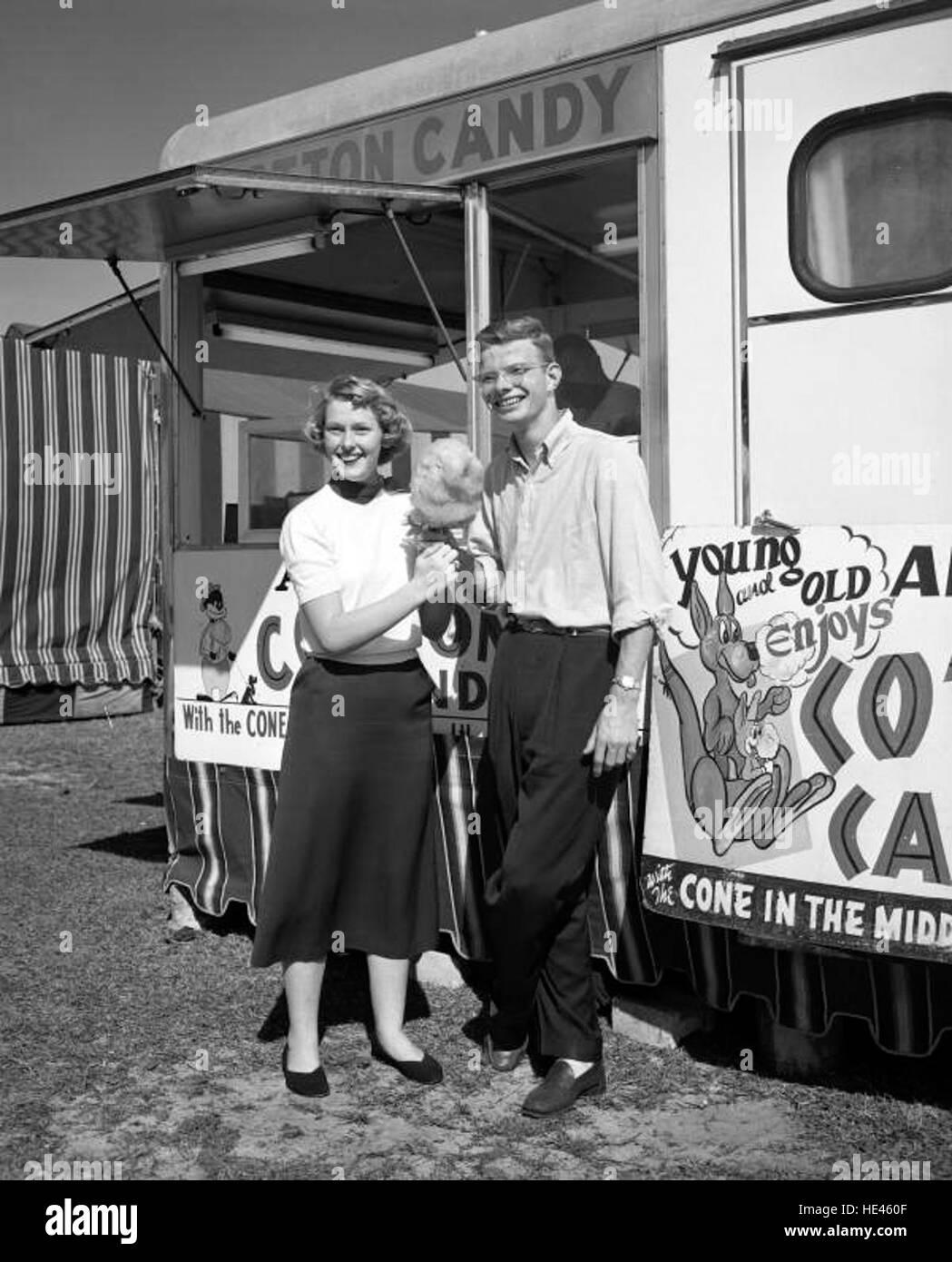 Kathryn Summers ed Ernie Thomas vengono catturati in questa fotografia storica, potendo con caramelle di cotone a una fiera o a un carnevale. L'immagine offre uno sguardo sulle attività ricreative e sulla moda di un'epoca passata. Foto Stock