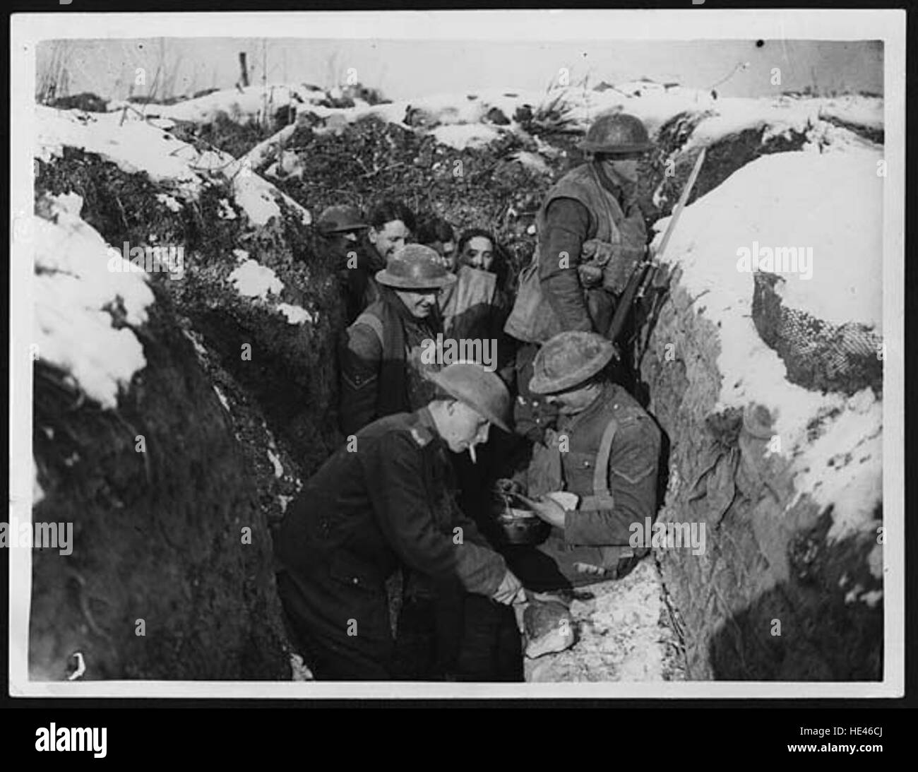 Questa immagine raffigura soldati, chiamati "Tommies", che mangiano in trincea durante la guerra. Serve come un forte ricordo delle dure condizioni che i soldati hanno affrontato durante il conflitto, riflettendo le realtà quotidiane della guerra e della vita militare in un'epoca passata. Foto Stock Questa immagine raffigura soldati, chiamati "Tommies", che mangiano in trincea durante la guerra. Serve come un forte ricordo delle dure condizioni che i soldati hanno affrontato durante il conflitto, riflettendo le realtà quotidiane della guerra e della vita militare in un'epoca passata. Foto Stock