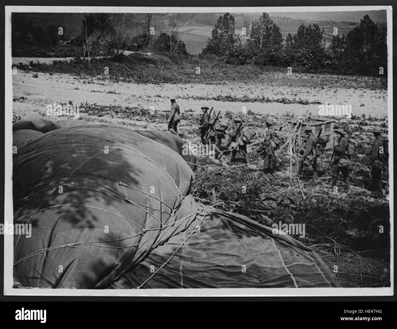 Questa immagine storica mostra i soldati britannici (Tommies) che passano un pallone di osservazione durante la prima guerra mondiale. I palloni di osservazione sono stati utilizzati per la ricognizione aerea, fornendo preziose informazioni durante le battaglie, specialmente nelle prime fasi della guerra. Foto Stock