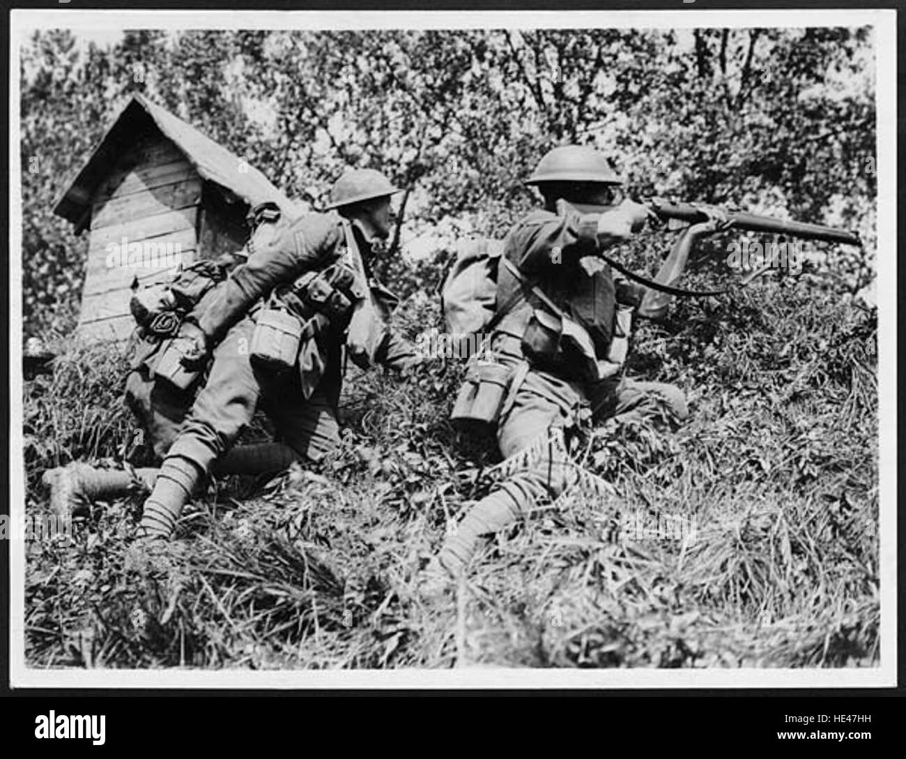 Questa immagine storica cattura un momento di azione militare, raffigurando soldati che sparano nelle forze tedesche in avanzata mentre tengono una testa di ponte critica durante la guerra. Foto Stock