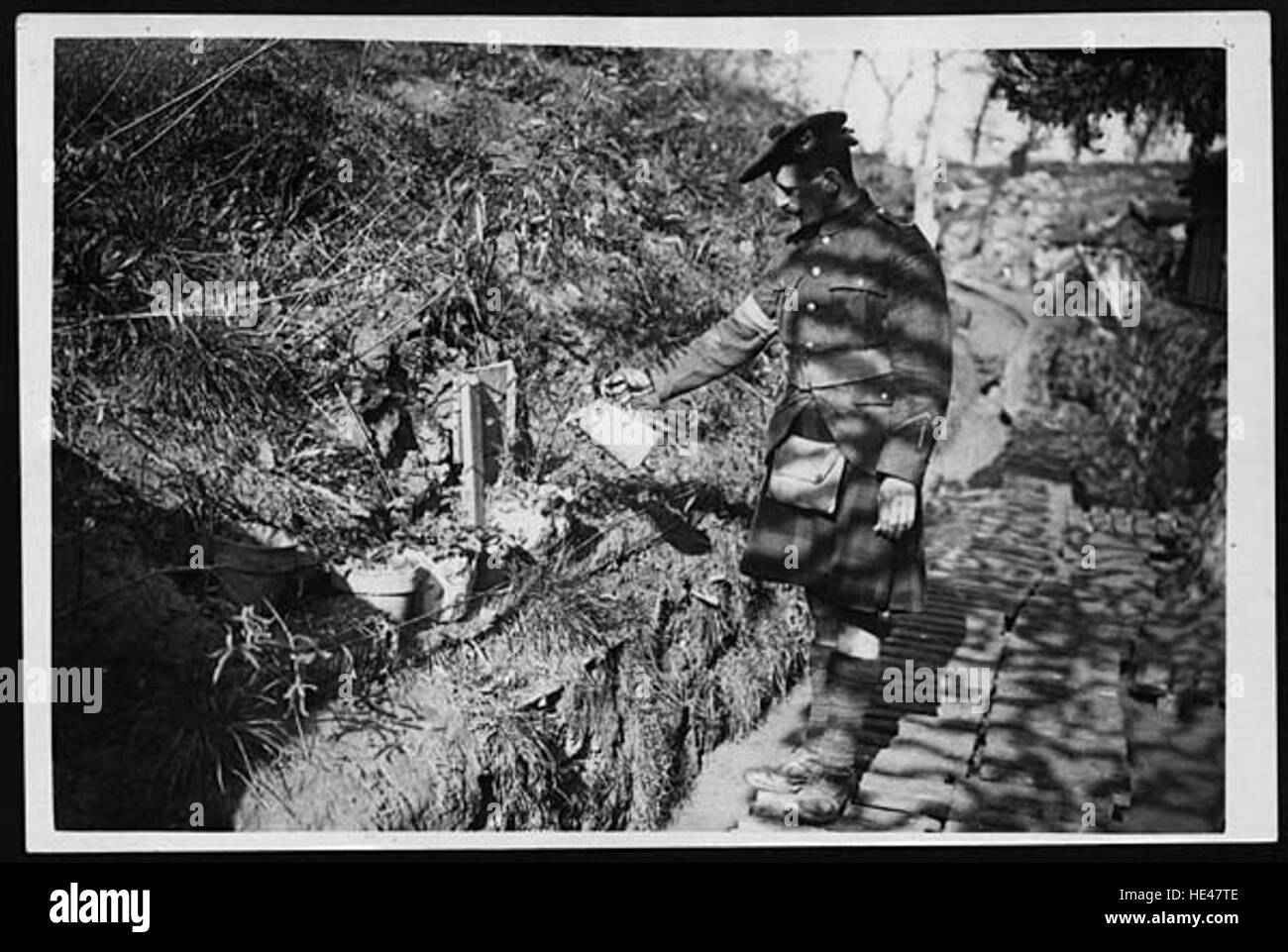 Questa immagine ritrae un Highlander, in abito tradizionale, che innaffiava fiori che ha piantato all'esterno. Rappresenta il legame con la natura e la vita pastorale spesso associata alle Highlands scozzesi. Foto Stock