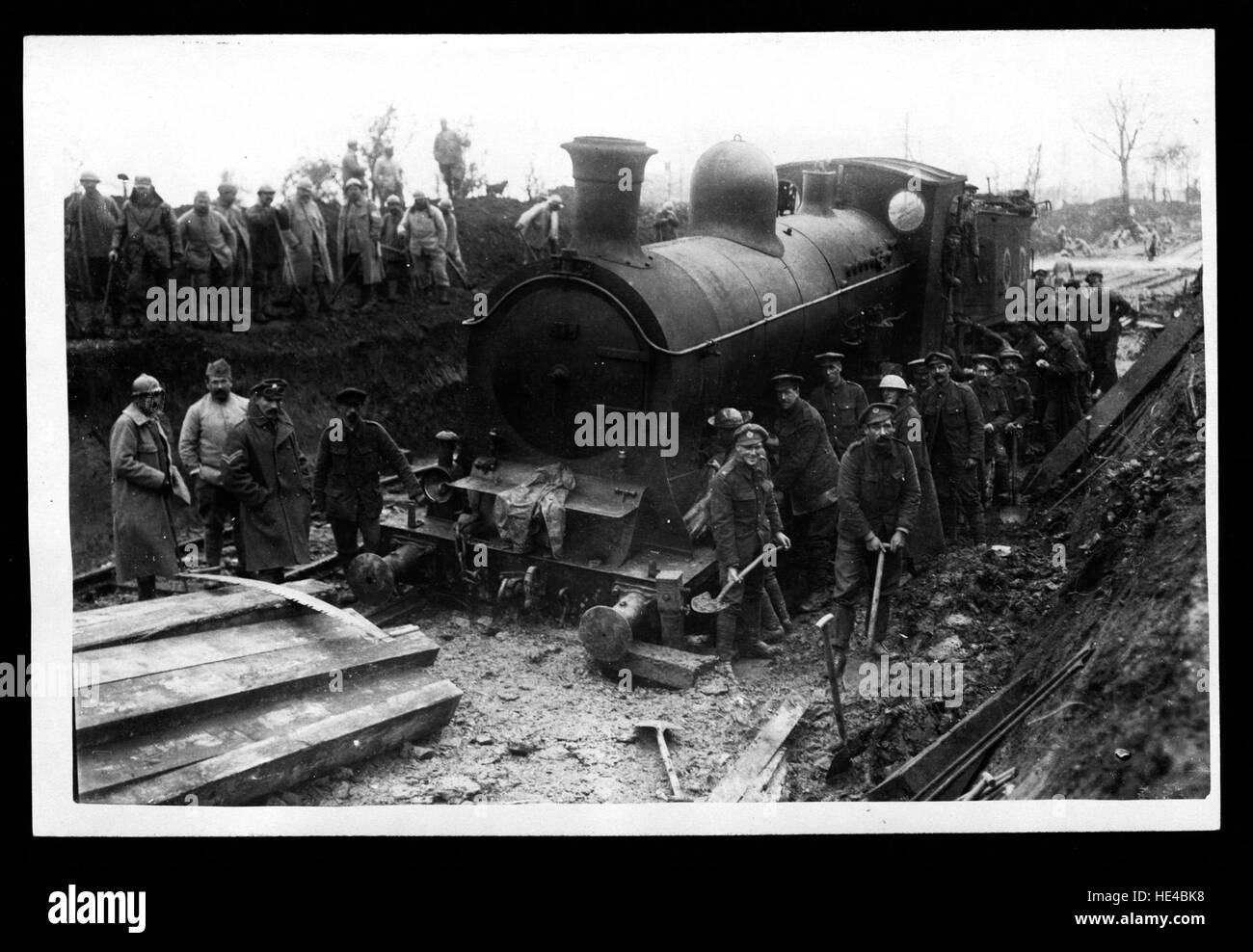 Questa immagine della prima guerra mondiale raffigura un motore ferroviario bloccato nel fango, catturando le difficoltà incontrate dai soldati e dalle attrezzature militari durante il conflitto. La foto evidenzia le sfide della logistica bellica e del trasporto in condizioni difficili. Foto Stock