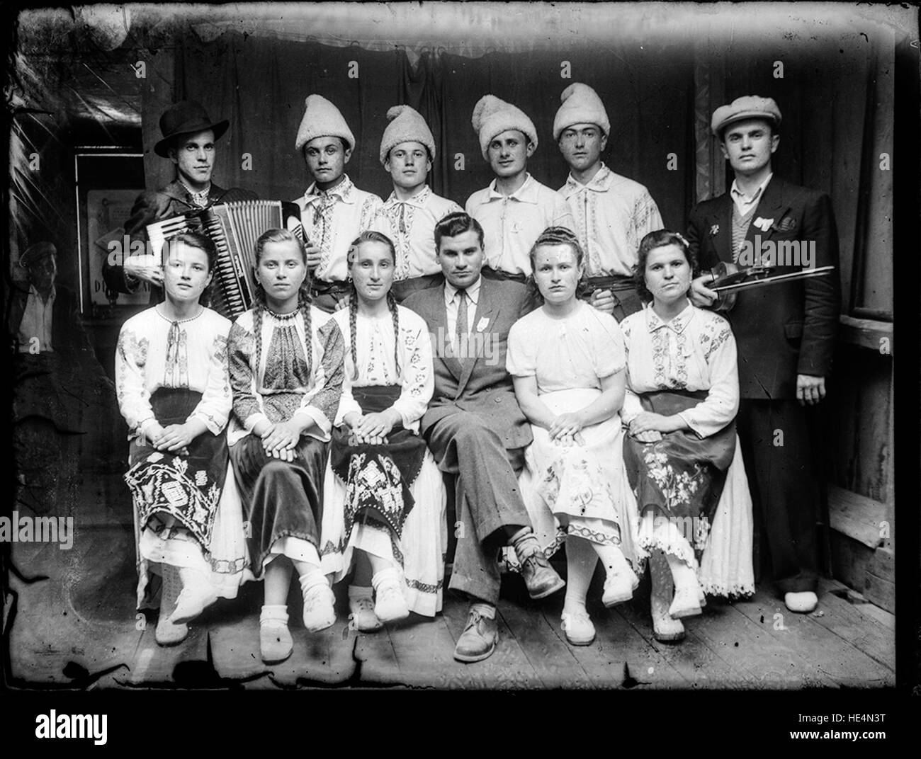 Ensemble, costumi tradizionali, Costica Acsinte, Ialomita, Romania, foto storica, ritratto di gruppo, fisarmonica, violino, lastre di vetro, immagine storica, Romania rurale, abbigliamento tradizionale, storia sociale, patrimonio culturale, bianco e nero, soggetti umani, tradizioni rurali, cultura rumena, foto senza tempo, vintage, archivio storico, villaggio rumeno, foto candide, nostalgico, musica popolare, vita di villaggio, strumenti tradizionali, xx secolo, vita di comunità, archivio fotografico, costumi sociali, patrimonio rumeno Foto Stock