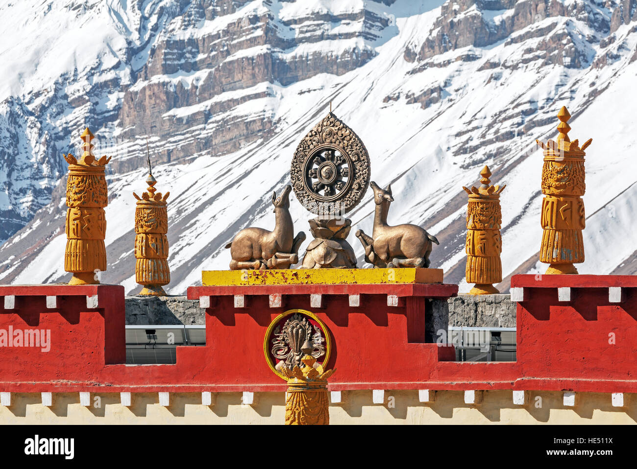 Ruota di Dharma sul tetto di un tibetano tempio Buddista sullo sfondo di montagne innevate. Foto Stock