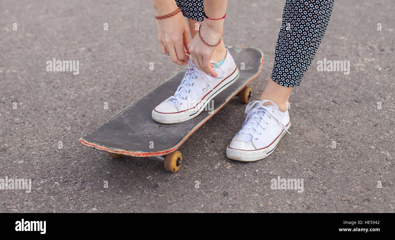 La donna sullo skateboard legatura di lacci delle scarpe Foto Stock