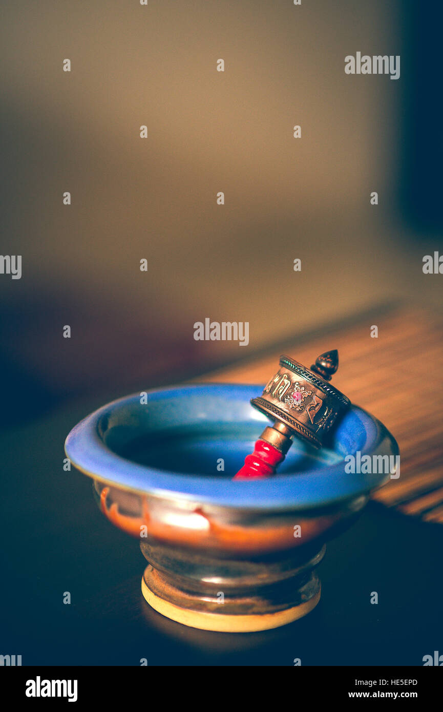 Un piccolo colorato la preghiera buddista ruota in un blu vaso in ceramica con sfondo sfocato Foto Stock