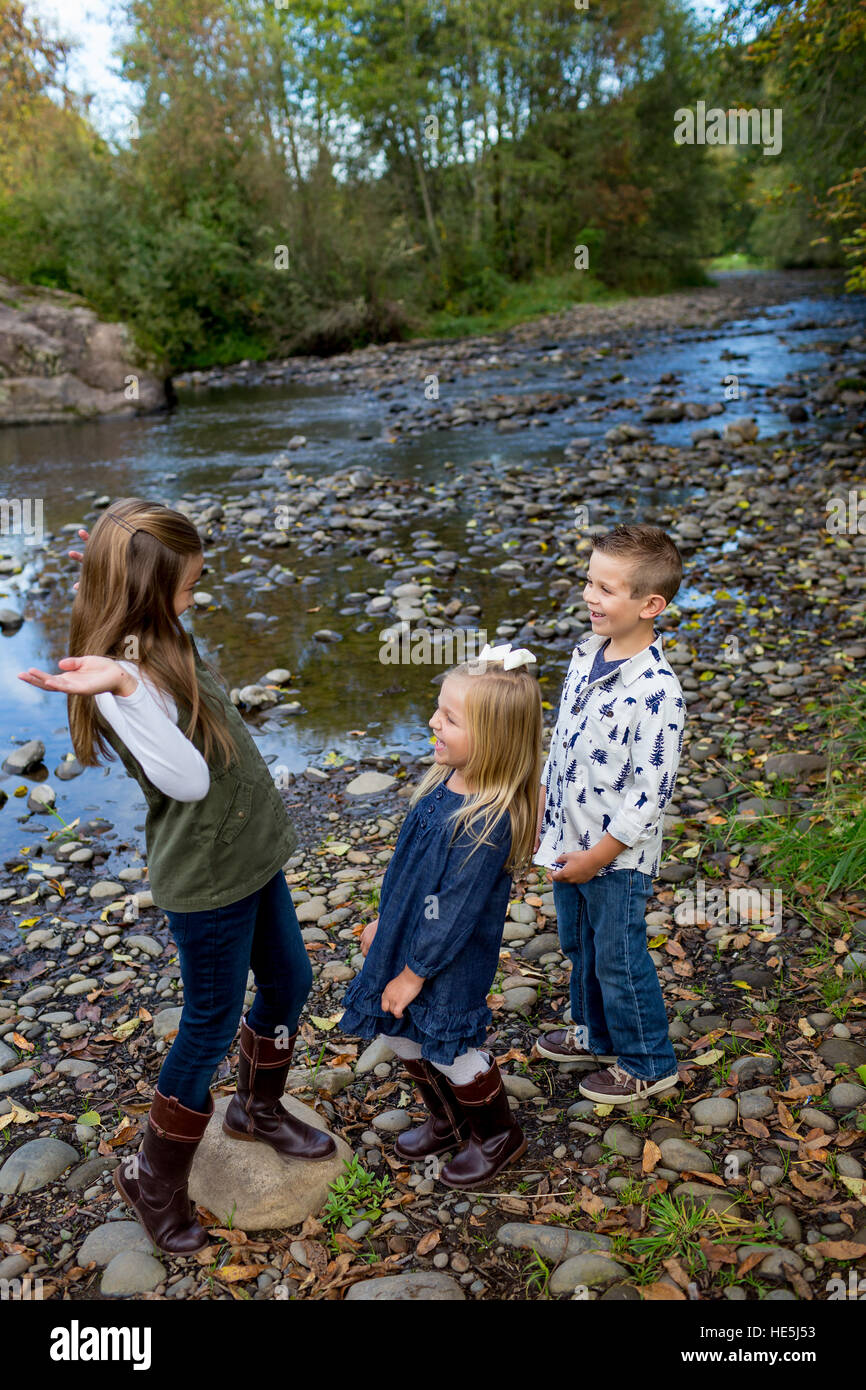 Tre bambini che sono fratelli in una candida foto all'aperto lungo le rive del fiume McKenzie in Oregon. Foto Stock