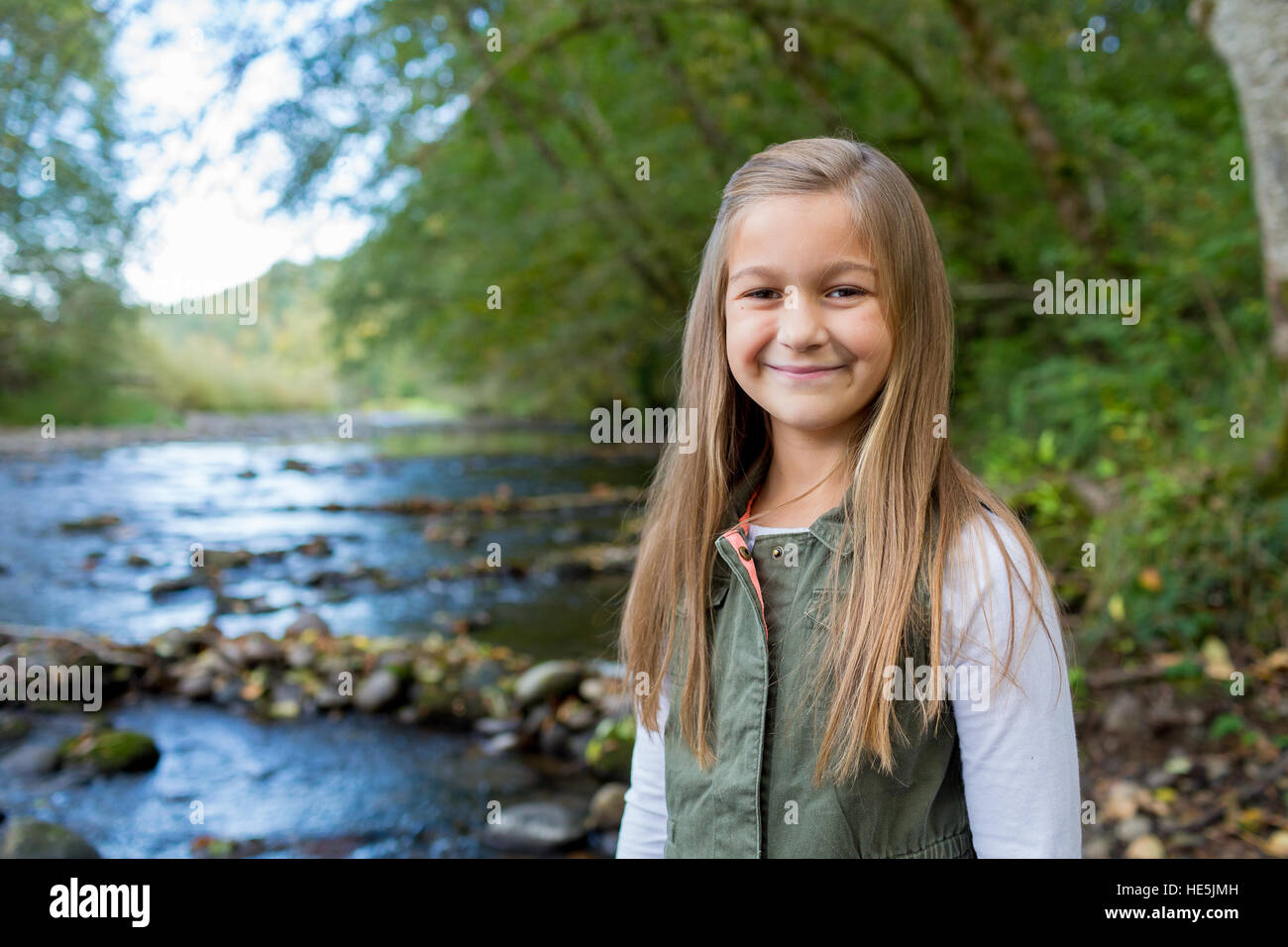 Giovane ragazza in un giubbotto verde in posa per un ritratto di uno stile di vita all'aperto lungo le rive del fiume McKenzie in Oregon. Foto Stock
