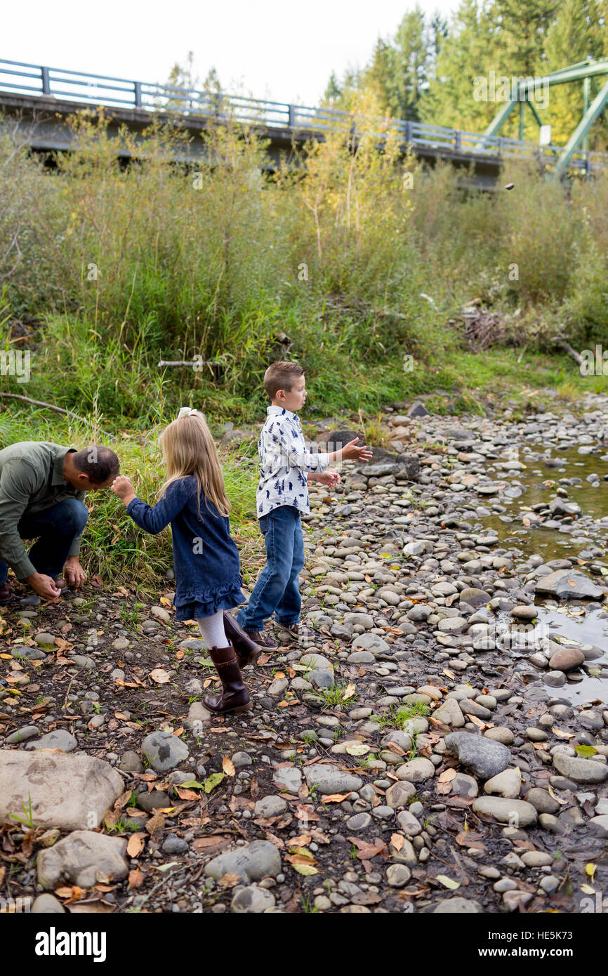 I fratelli gettare pietre nel fiume McKenzie insieme nel colpo di stile di vita dei bambini che si divertono a giocare. Foto Stock