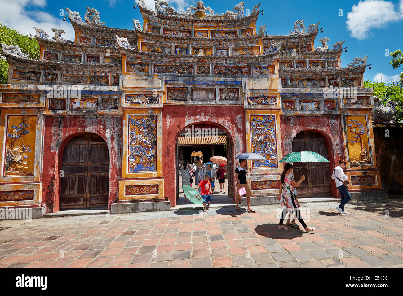 I turisti che camminano attraverso un cancello d'ingresso ornato al complesso del Tempio di Mieu. Città imperiale (la Cittadella), Hue, Vietnam. Foto Stock