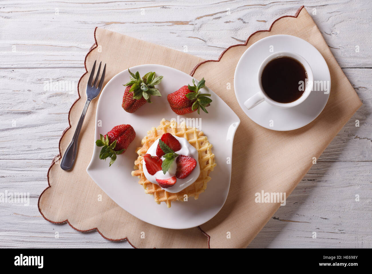 Cialde con fragole fresche, la crema di latte e caffè su una tabella. Orizzontale vista superiore Foto Stock